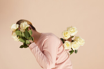 Young man with white rose bouquets in sleeves hiding his face from camera