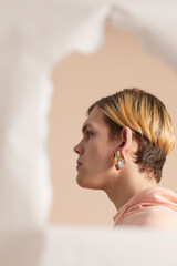 Portrait of stylish feminine male model with golden earring in profile