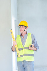 Supervisor male engineer wearing a protective vest and safety hard hat.in construction site for building site survey in civil engineering project.