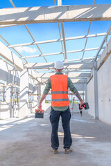 Fototapeta premium Male engineer wearing safety suit and hard hat holding toolbox and electric drill in construction site for building site survey in civil engineering project.