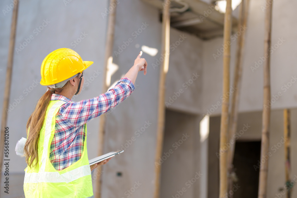 Wall mural Asia Female civil engineer with inspecting construction plans at building site of high-riser building site survey in civil engineering project.