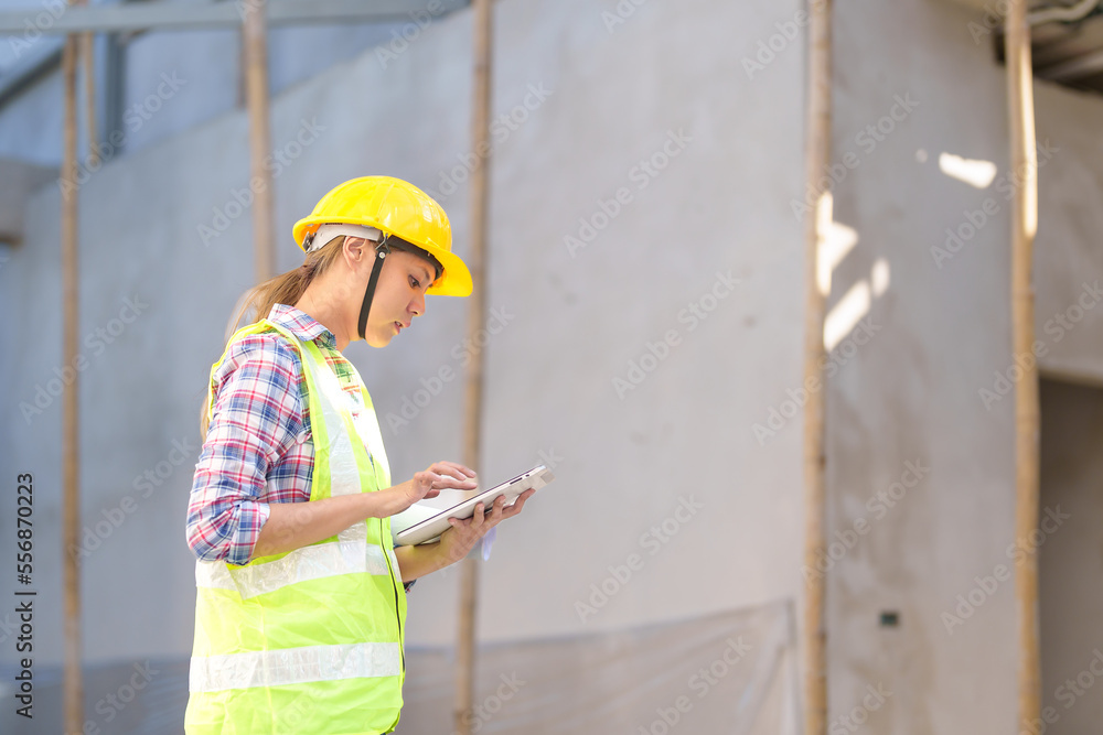 Wall mural asia female civil engineer with inspecting construction plans at building site of high-riser buildin