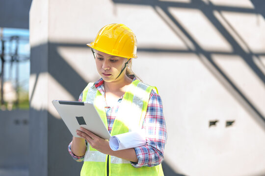 Asia Female civil engineer with inspecting construction plans at building site of high-riser building site survey in civil engineering project.