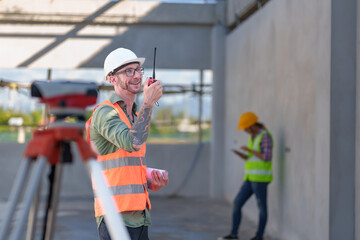 Two professionals inspect construction site of commercial building, industrial building, real estate project  civil engineer, investor using laplet in background crane, skyscraper, concrete formwork