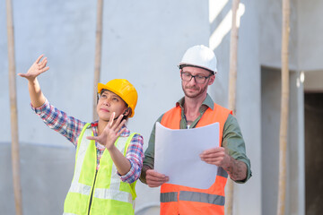 Two professionals inspect construction site of commercial building, industrial building, real estate project  civil engineer, investor using laplet in background crane, skyscraper, concrete formwork