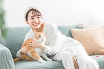 家のソファで猫を抱っこする飼い主のアジア人女性
