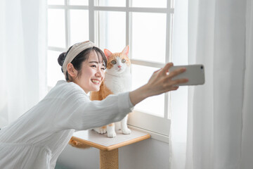 Fototapeta na wymiar 愛猫と一緒にスマホで写真を撮るアジア人女性 