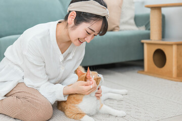 綿棒を使って猫の耳掃除をする飼い主のアジア人女性
