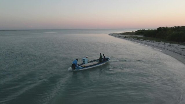 Fishermen going into the sea during sunset in a small motor boat in Isla Aguada, México.