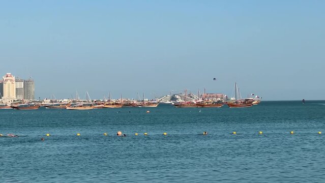 Traditional sailing vessels Boat Lenj Dhows in the landscape of Qatar Doha Arabian Persian Gulf GCC Red Sea and Indian Ocean region wind the sails blue color sea water towers hotels in west bay energy