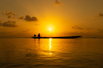Naklejka na ściany i meble Silhouette of fishermen on the lake with sunset sky.