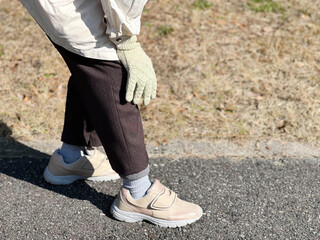 歩きながら膝をさする手袋をした手