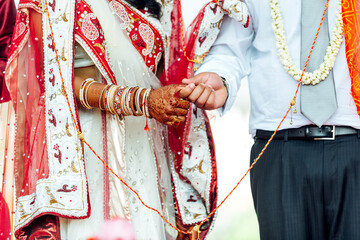 Indian wedding ceremony bride and groom holding hands together There are accessories such as rings,...