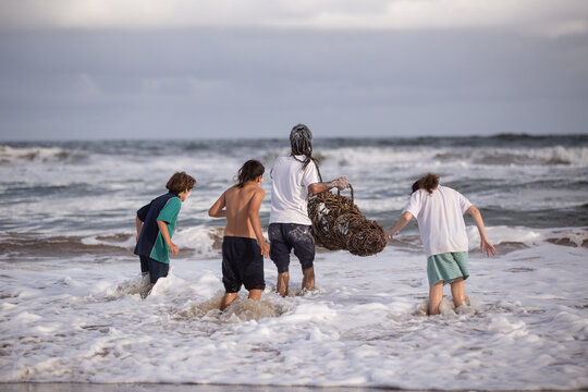 Aboriginal family playing in waves at a beach with fish trap