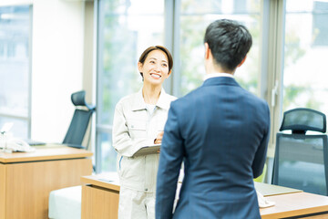 Fototapeta na wymiar 作業服を着た女性とスーツを着た日本人男性
