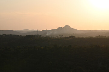 Silhouette image of a hill during sunset. Orange sky caused due to sunset.