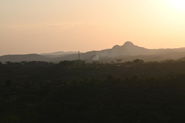 Silhouette image of a hill during sunset. Orange sky caused due to sunset.