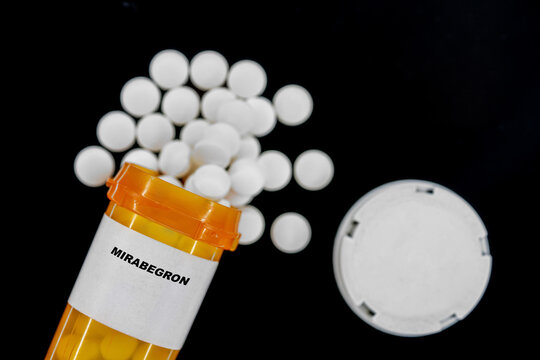 Mirabegron Rx medical pills in plactic Bottle with tablets. Pills spilling out from yellow container.