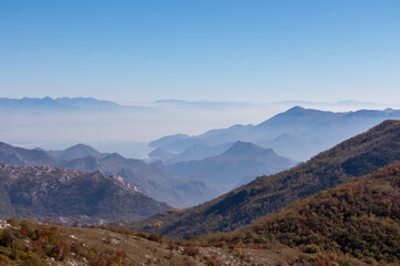 Fototapeta premium Panoramic view of dramatic karst mountain chains Dinaric Alps surrounding the Lake Skadar National Park seen from Goli Vrh, Montenegro, Balkan, Europe. Valley is covered by mystical fog, blue hills