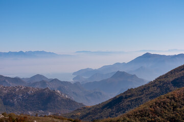 Panoramic view of dramatic karst mountain chains Dinaric Alps surrounding the Lake Skadar National Park seen from Goli Vrh, Montenegro, Balkan, Europe. Valley is covered by mystical fog, blue hills