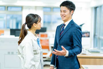 作業服を着た女性とスーツを着た日本人男性