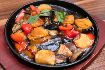 Delicious asian food in cast-iron pan on wooden background. Selective focus. Asian food concept