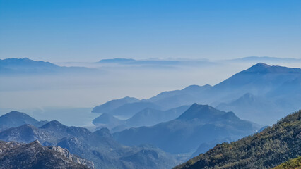 Fototapeta na wymiar Panoramic view of dramatic karst mountain chains Dinaric Alps surrounding the Lake Skadar National Park seen from Goli Vrh, Montenegro, Balkan, Europe. Valley is covered by mystical fog, blue hills