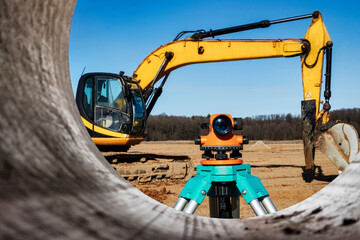 Level with an excavator in the background. Construction level or theodolite. Geodetic instruments...