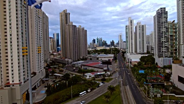 Drone shot of Panama skyline at sunrise while backtracking and Panama huge flag appears on a wide lens over the speedway