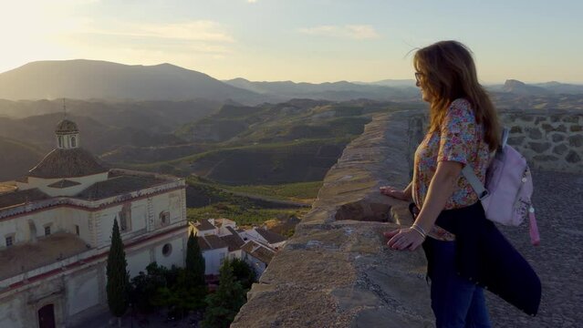 Tourist woman contemplating the spectacular views of the white village of Olvera at sunset over the mountains, Cadiz.