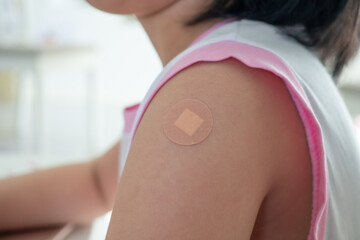 Vaccinated little asian girl with adhesive plaster after vaccine injection