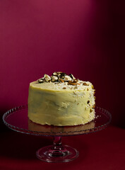 Festive banana cake in white chocolate, decorated with nuts, cookies and chocolate on the background of Viva Magenta, the color of 2023. exclusive pastries according to the author's recipes.copy space