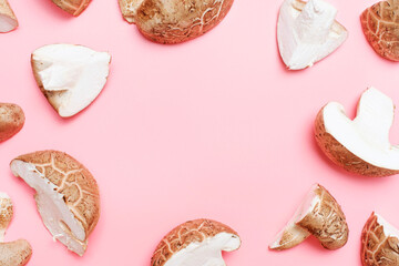 Cut shiitake mushrooms on pink background close-up, top view.