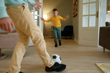 Emotional father and son playing football at home living room