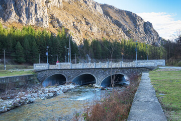Stone bridge over the mountain river. Bridge with pipes through which water passes.