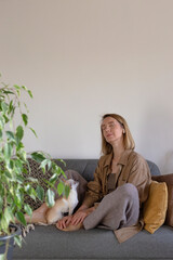 Woman at home resting and listening meditation on sofa.