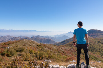 Fototapeta premium Man on top of Goli Vrh with scenic aerial view on dramatic mountain chains of Dinaric Alps surrounding Lake Skadar National Park, Montenegro, Balkan, Europe. Valley is covered by mystical fog. Freedom