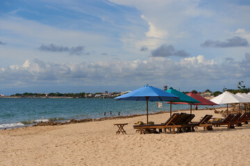 Beach scenery, sun loungers with umbrellas on a sandy beach in the sea bay