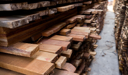 Piles of  Mixed wood  Pine wood  in the sawmill, planking. Warehouse for sawing boards on a sawmill outdoors. Wood timber stack of wooden blanks construction material Industry.
