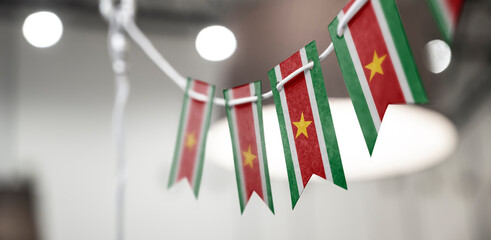 A garland of Suriname national flags on an abstract blurred background