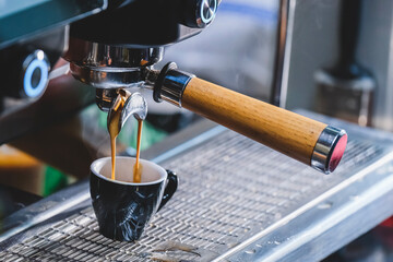 Close-up of espresso pouring from the coffee machine at the cafe. Professional barista coffee brewing.