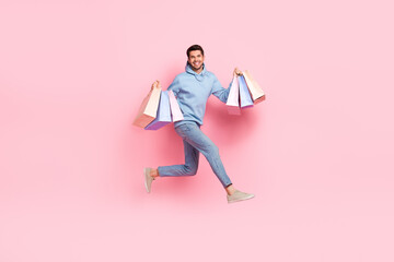 Fototapeta na wymiar Full length photo of cheerful man wear stylish blue clothes carry bags moving empty space mall center isolated on pink color background