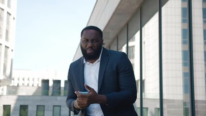 Successful manager shows off the money he has earned by showing wad of dollars. African american top manager demonstrating his business success by showing the cost of earned money standing in downtown