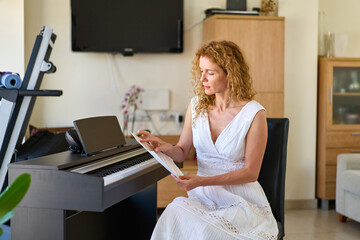 Woman in white dress sitting at the piano. Woman playing piano were digitally modified.