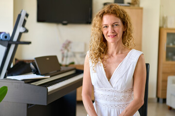 Woman in white dress sitting at the piano. Woman playing piano were digitally modified.