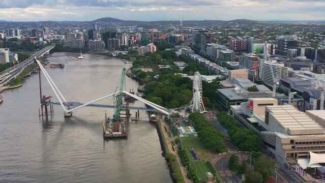 Panoramic aerial view fly around Brisbane city capturing building progression of neville bonner bridge connecting south bank and central business district and the star casino queen's wharf tower.