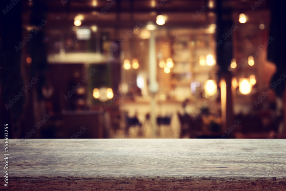 Wall mural background Image of wooden table in front of abstract blurred restaurant lights