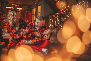 Candid authentic cute happy family in red plaid pajamas spends time together at lodge Xmas decorated