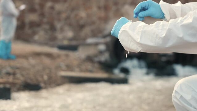 Ecologist sampling water from the river with test tube, Biologist wear protective suit and mask collects sample of waste water from industrial, problem environment, scientist environmentalist