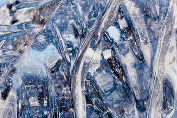 Bubbles and cracks inside natural ice. A fragment of a festive ice figure before Christmas and New Year. Optical phenomena. Abstract background. Close up. Selective focus.